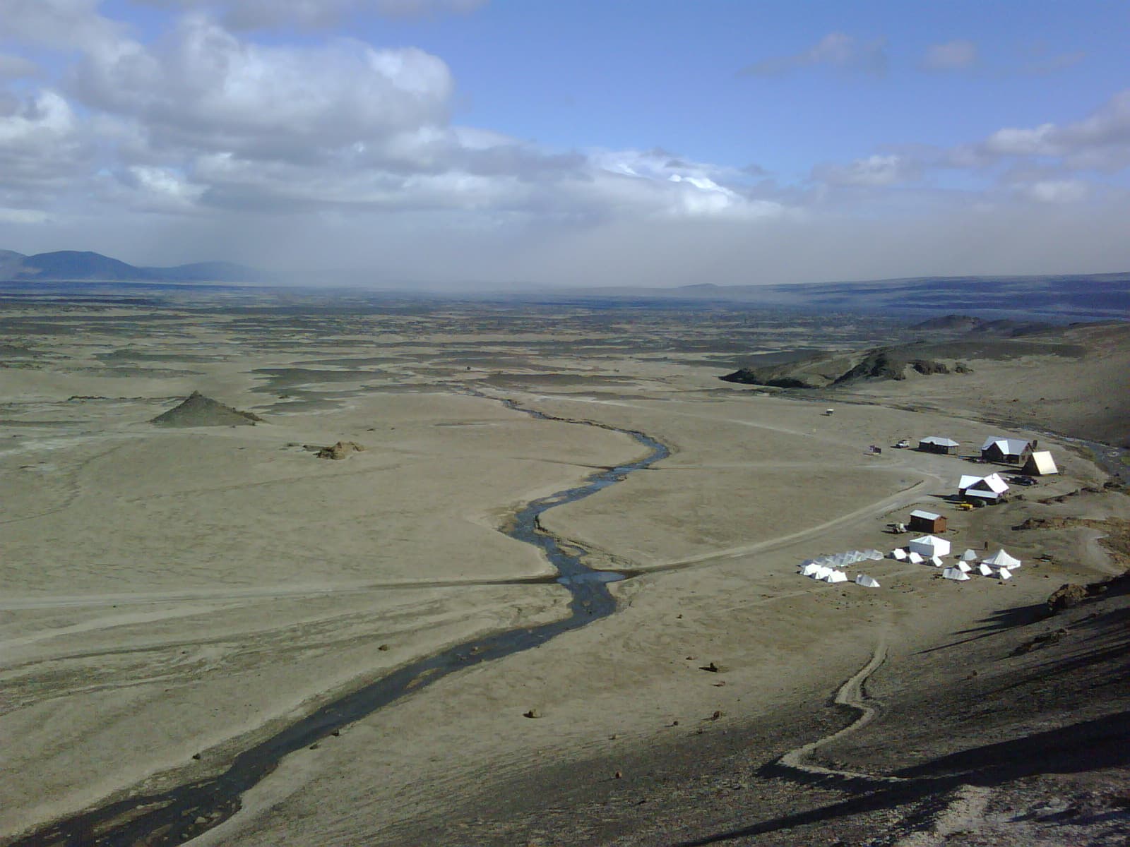 Ódáðahraun lava desert seen from Askja with huts, a stream, and wide highland plains below.