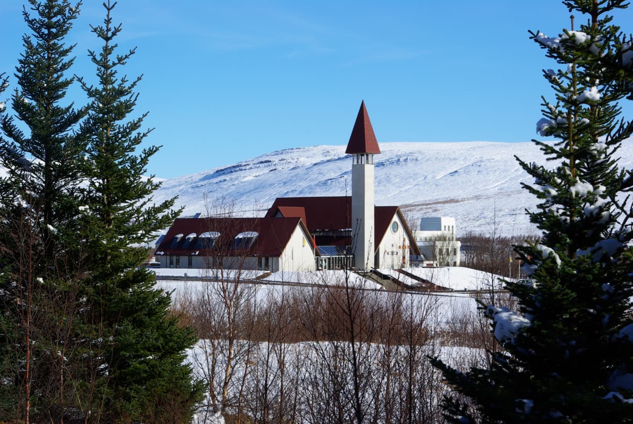 Snorrastofa and Reykholt church buildings in snow below pale hills