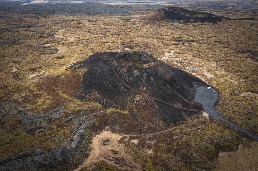 Aerial view of Saxhóll crater with the stair path, parking area, and surrounding lava field.