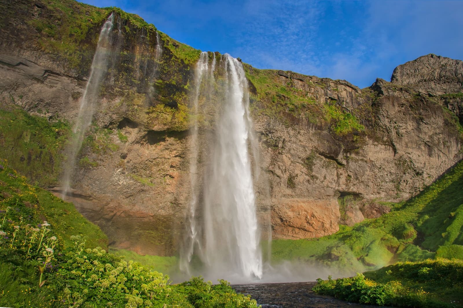 Seljalandsfoss waterfall dropping from green cliffs on the South Coast of Iceland.