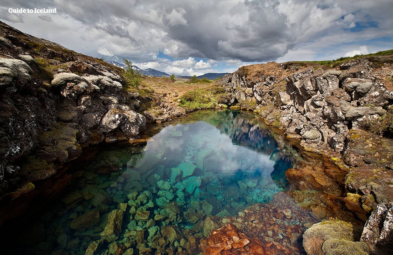 Clear blue Silfra fissure water running between dark volcanic rock walls in Þingvellir.