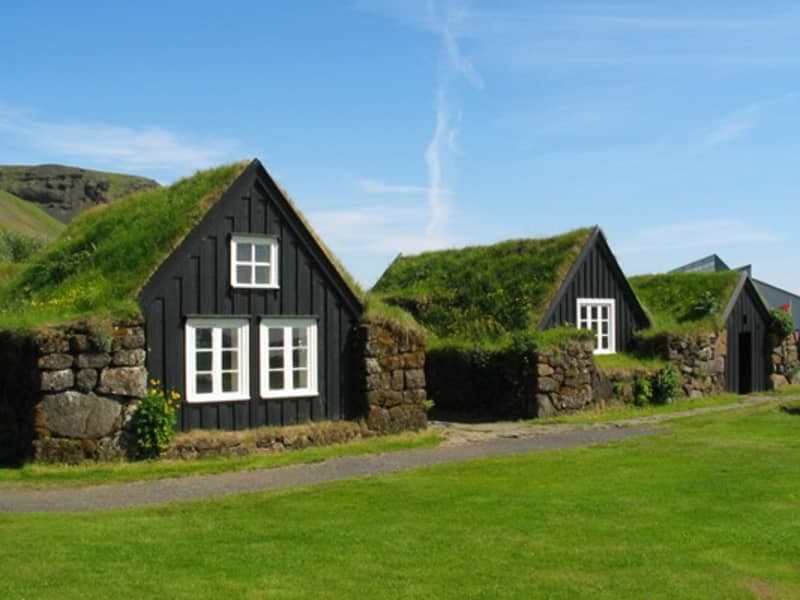 Black turf-roofed houses at Skógar Museum on a clear South Iceland day.