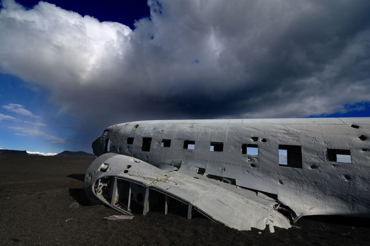 The Sólheimasandur DC-3 plane wreck beneath heavy clouds on the black sand plain.