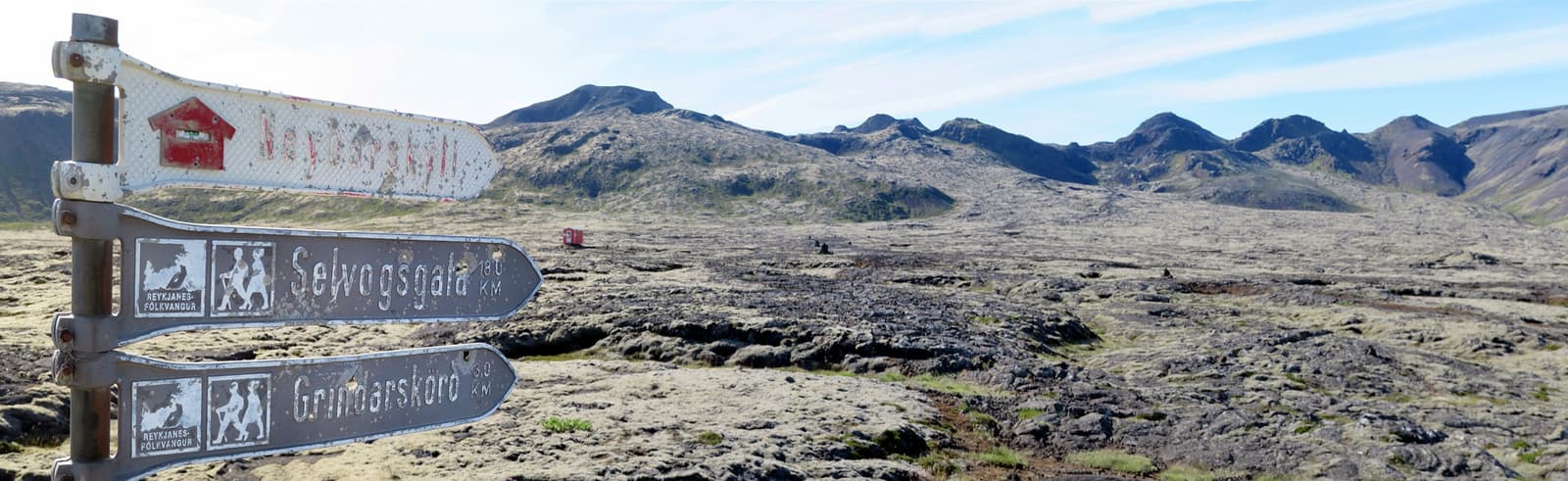 Weathered trail signs and lava fields below the Stóri-Bolli and Grindarskörð volcanic hills.