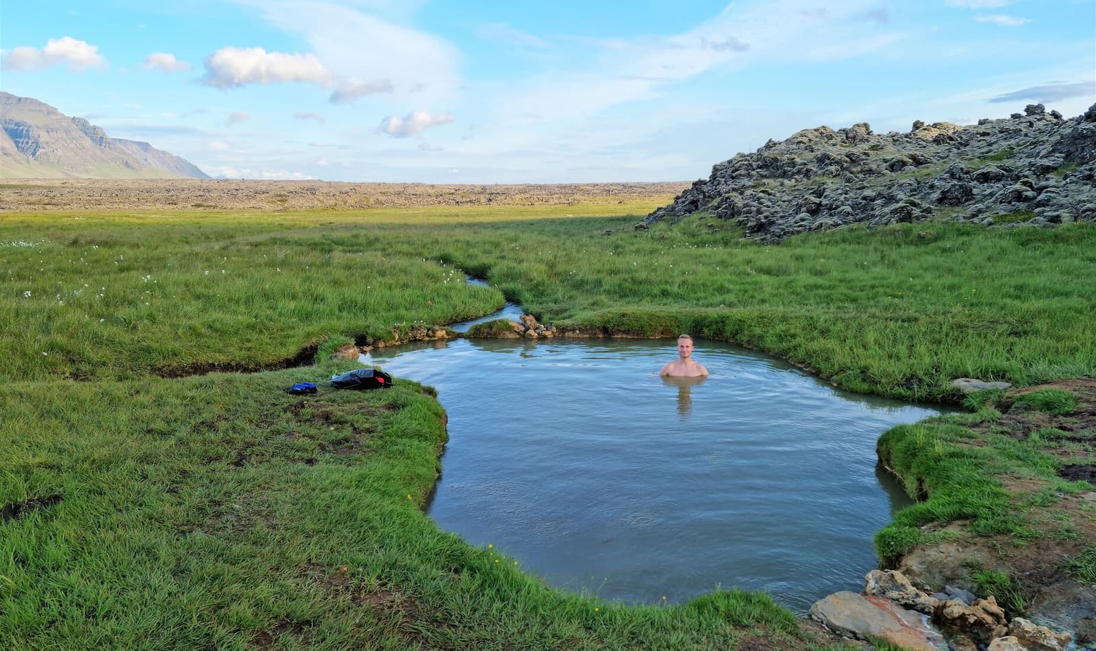 Sturlungalaug Hot Springs pool in grassy lava-country terrain on eastern Snæfellsnes.