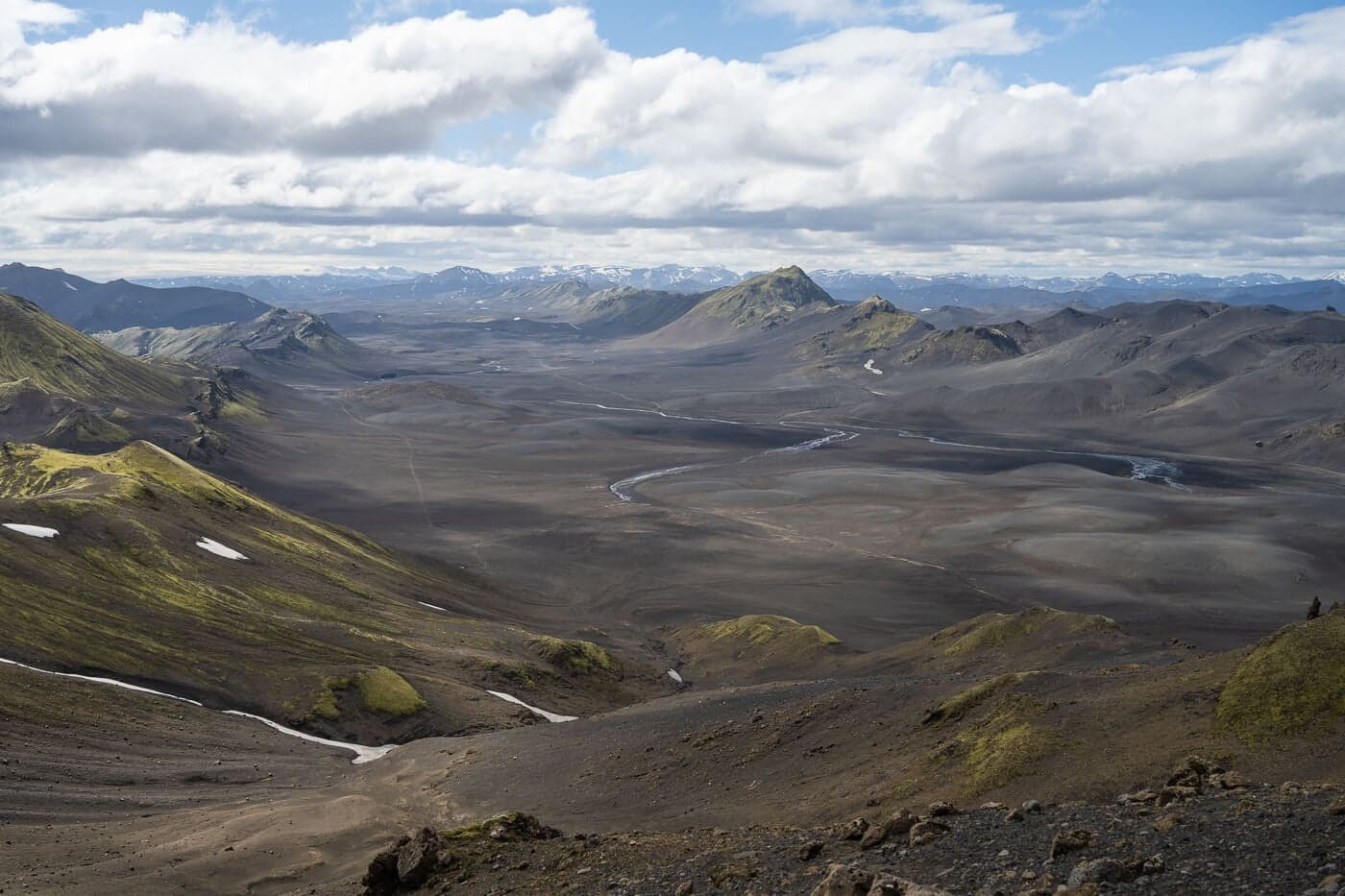 Remote highland view south from Sveinstindur across dark valleys, rivers, and green ridges.