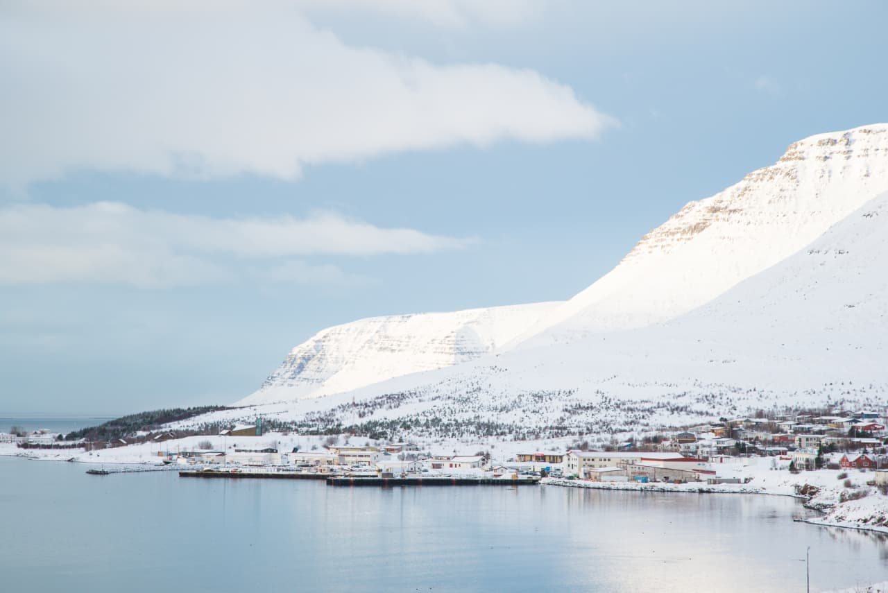 Snow-covered Tálknafjörður harbor and village beside calm Westfjords water.