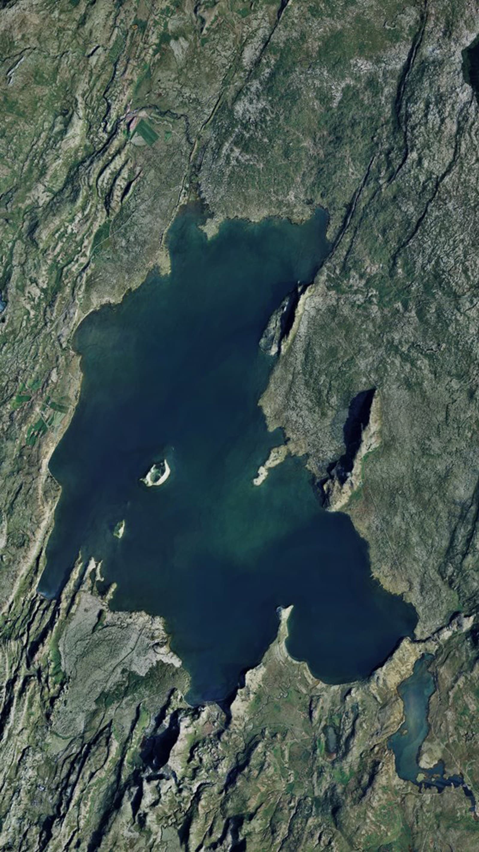 Aerial view of Lake Þingvallavatn surrounded by rift lines, lava terrain, and smaller water bodies.