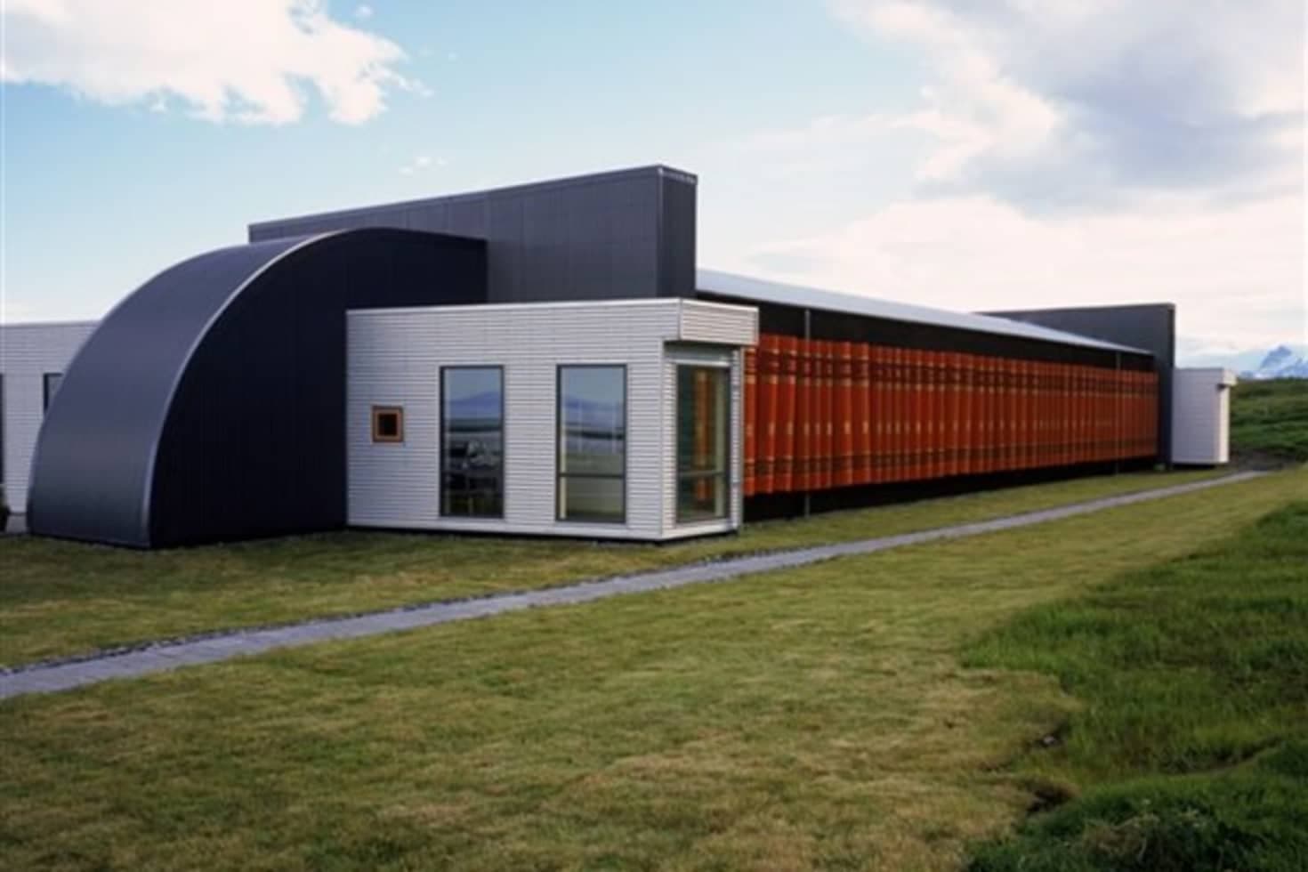 Þórbergssetur exterior at Hali with its red book-spine wall and mountains behind the museum.