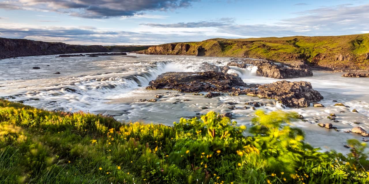 Urriðafoss spreading across the Þjórsá river with dark rock ledges and green riverbank in South Iceland.