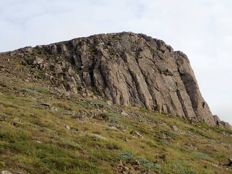 The basalt cliff of Valshamar above grassy slopes in Eilífsdalur near Hvalfjörður.