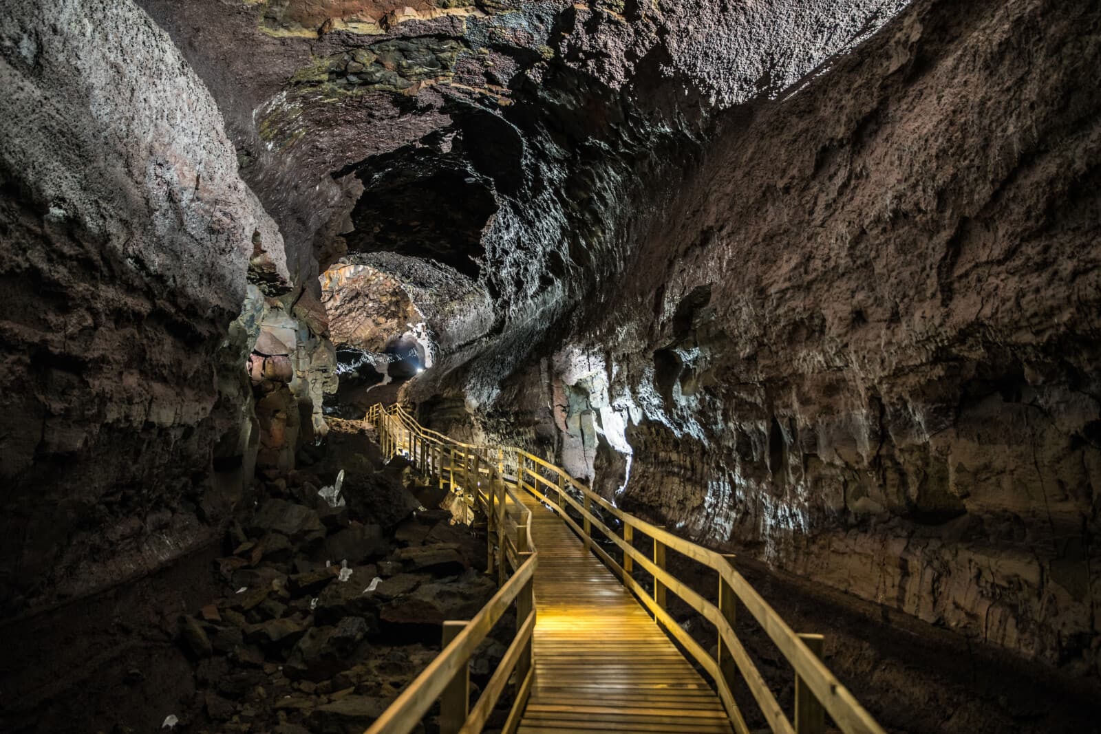 Wooden walkway running through the broad interior of Víðgelmir lava cave in West Iceland.
