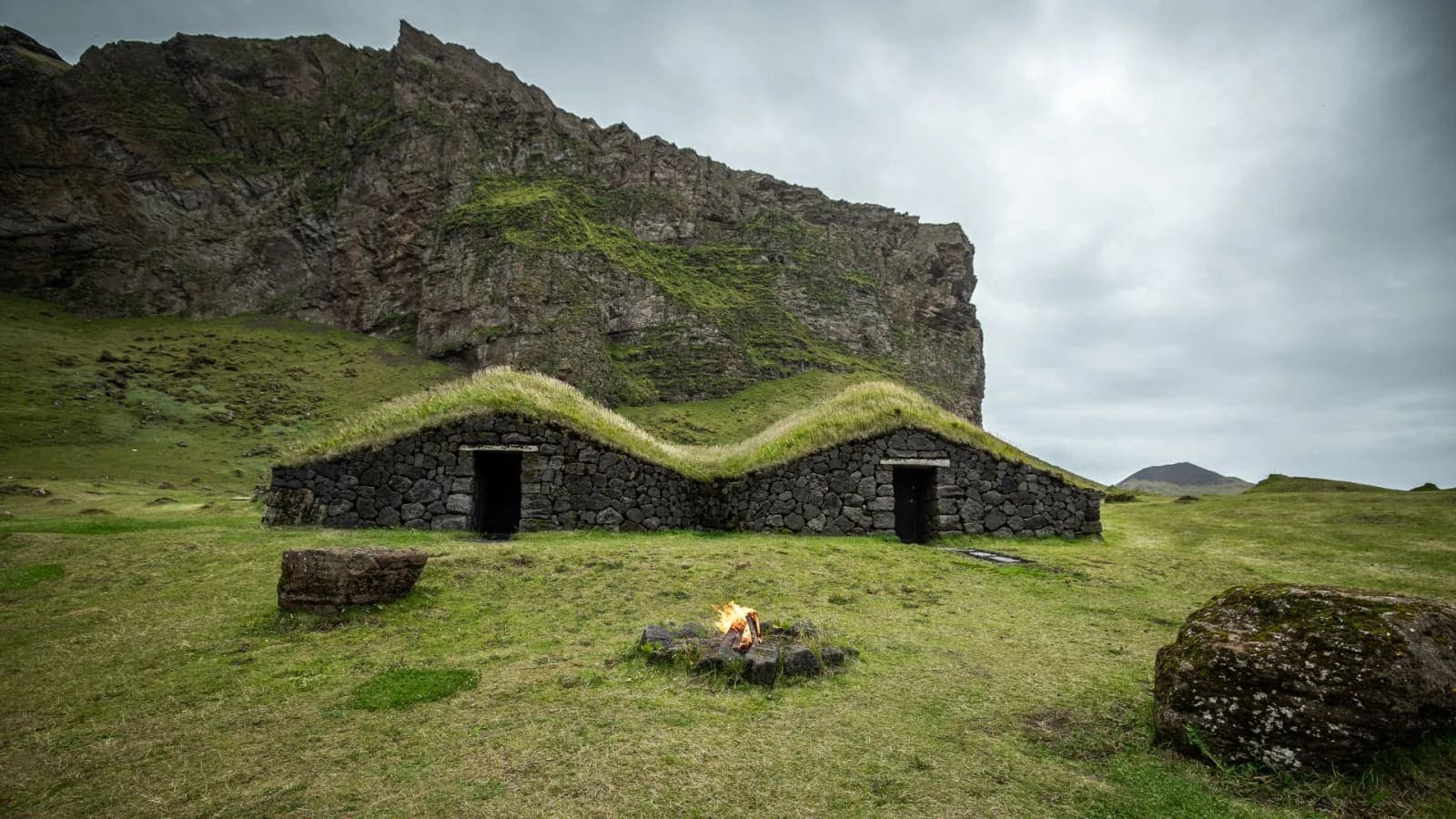 Reconstructed turf-and-stone house of Herjólfsbær Viking Town beneath the cliffs of Herjólfsdalur