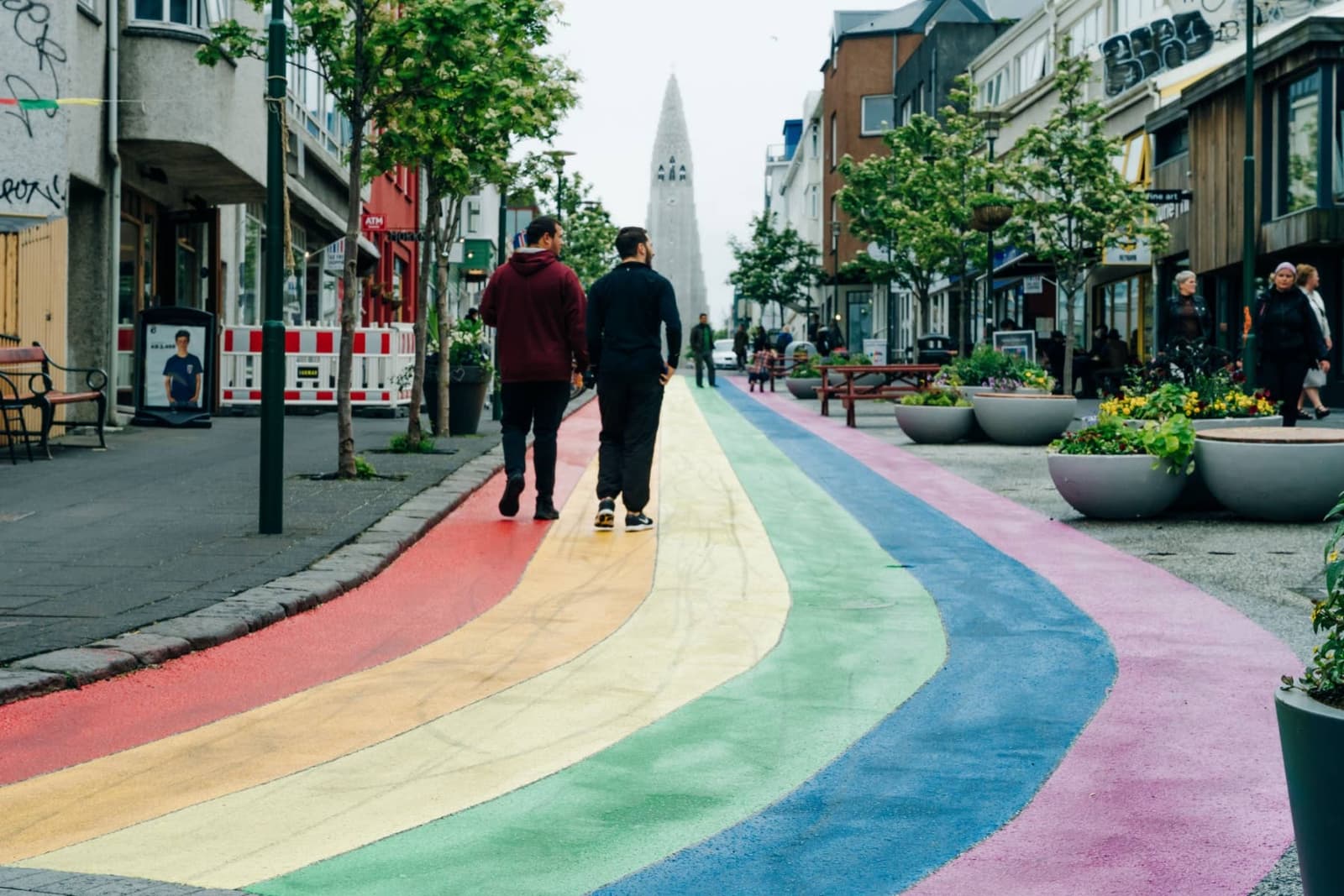 People walking along the rainbow-painted Skólavörðustígur street toward Hallgrímskirkja in Reykjavík.