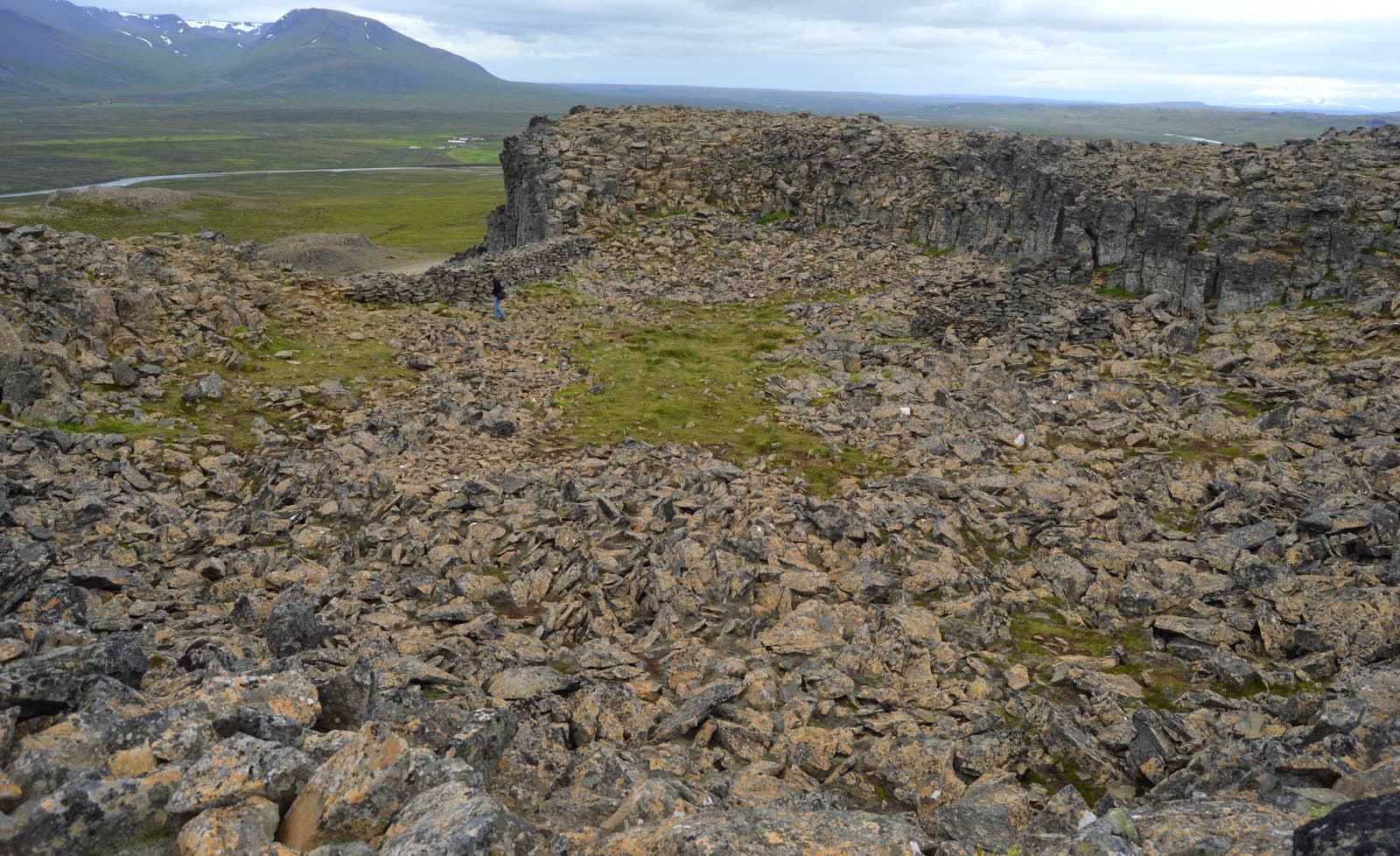 Rocky basalt enclosure at Borgarvirki with North Iceland countryside beyond.
