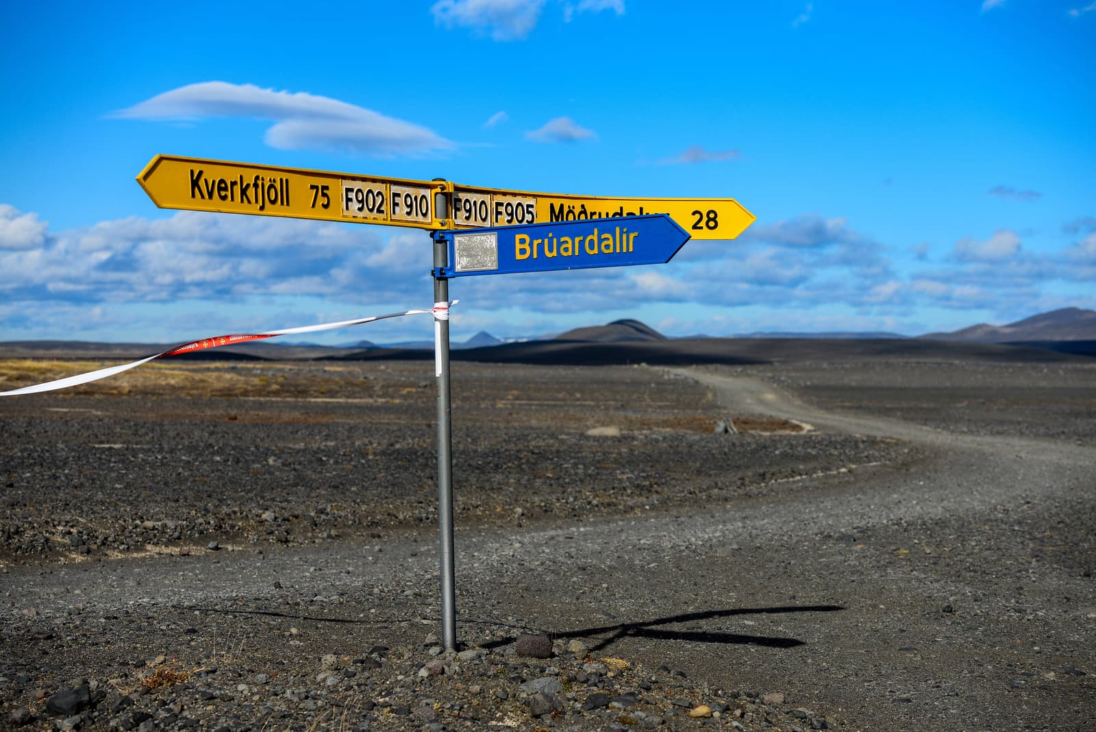 Brúardalir highland road sign with gravel terrain and distant mountains in the East Highlands.