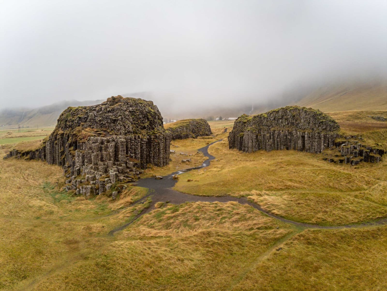 Wide view over the Dverghamrar basalt-column outcrops and walking paths in South Iceland.