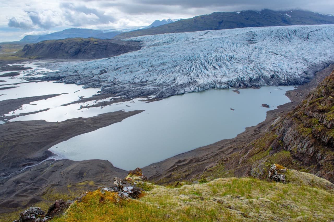 Fláajökull glacier and its pale lagoon below dark mountains in southeast Iceland.