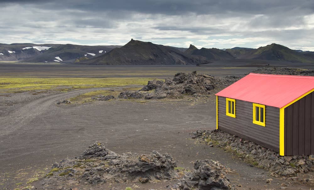 Jökulheimar hut beside black lava, mossy flats, and dark Highlands mountains near Vatnajökull.