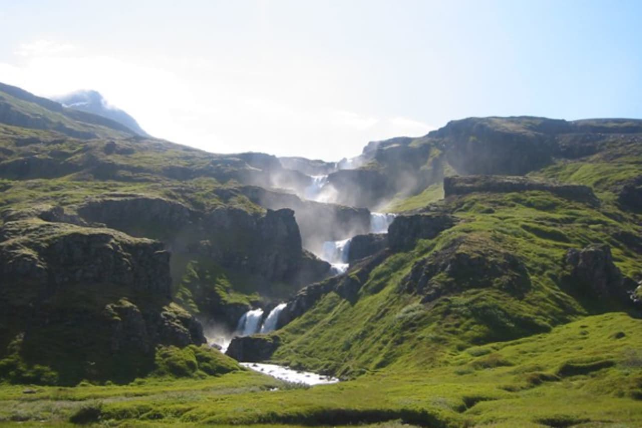 Klifbrekkufossar Waterfalls stepping down green cliffs in Mjóifjörður, East Iceland.