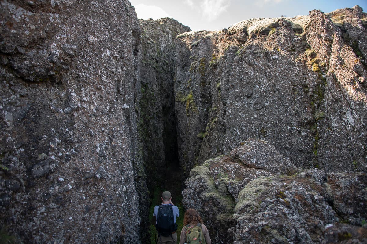 Hikers descending into the entrance of Lambafellsgjá on the Reykjanes Peninsula.