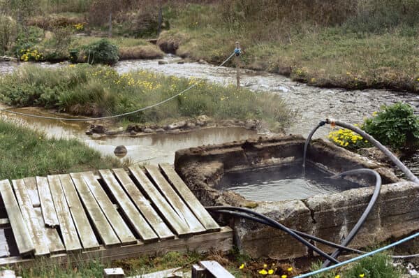 Small concrete-edged Marteinslaug hot spring beside a stream near Haukadalur.
