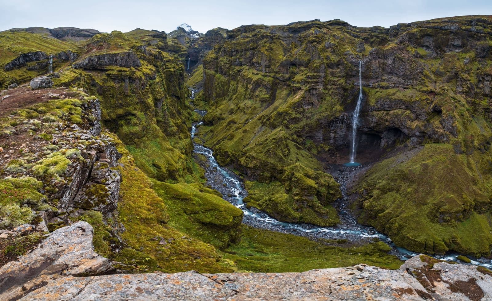Múlagljúfur Canyon with mossy walls, winding river, and waterfalls seen from the rim trail in southeast Iceland.