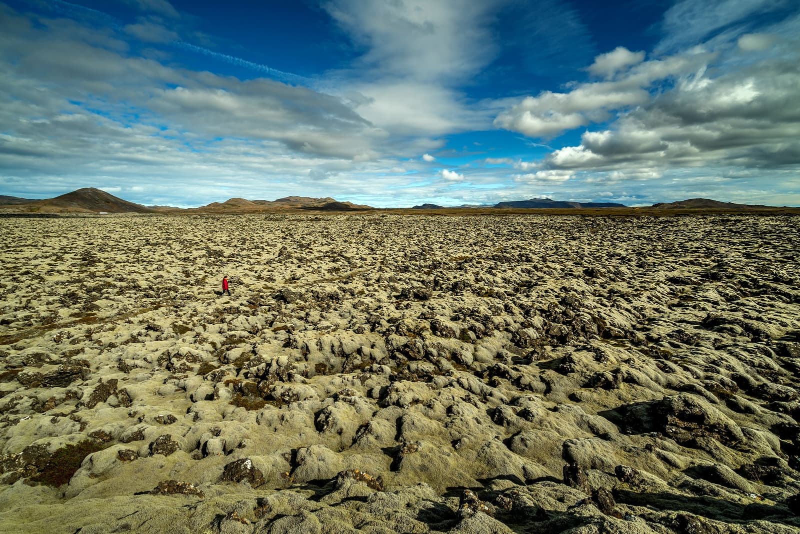 Wide view over moss-covered Ögmundarhraun lava field with low Reykjanes mountains beyond.