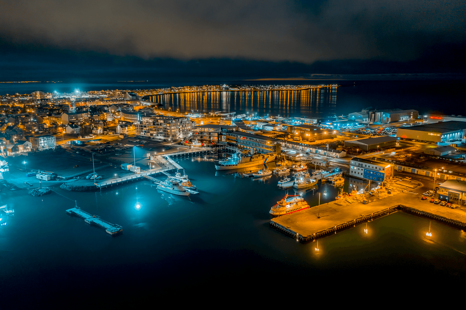 Aerial night view of Reykjavík Old Harbour with lit quays, boats, and the city waterfront