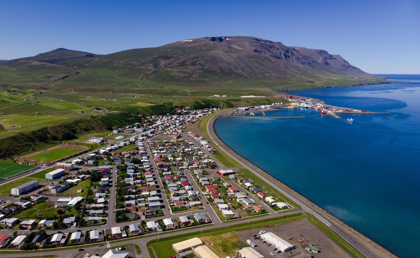 Aerial view of Sauðárkrókur town, harbor, Skagafjörður water, and Tindastóll mountain in North Iceland.