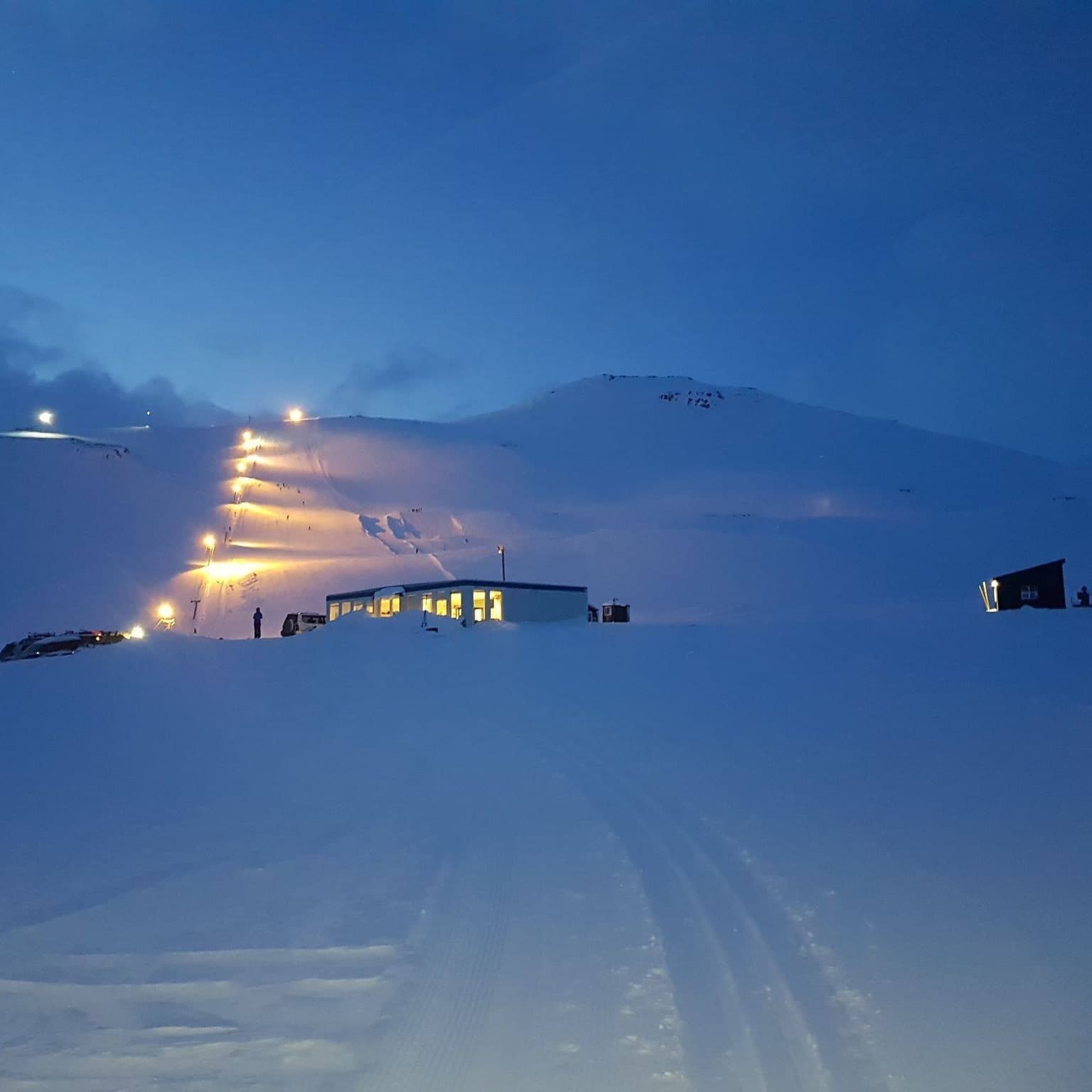Floodlit snowy slopes and ski tracks at Stafdalur Ski Station above Seyðisfjörður.