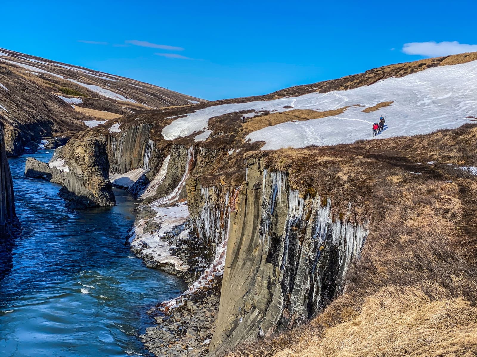Wide view of Stuðlagil Canyon with a blue river running between dark basalt walls in East Iceland.