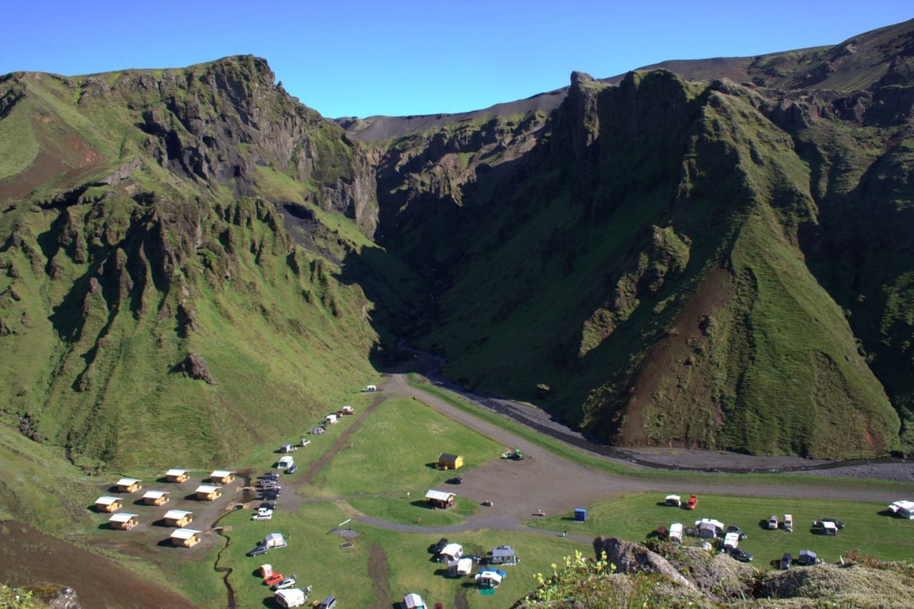 Þakgil Canyon opening into a sheltered green campsite basin beneath steep moss-covered cliffs near Vík.