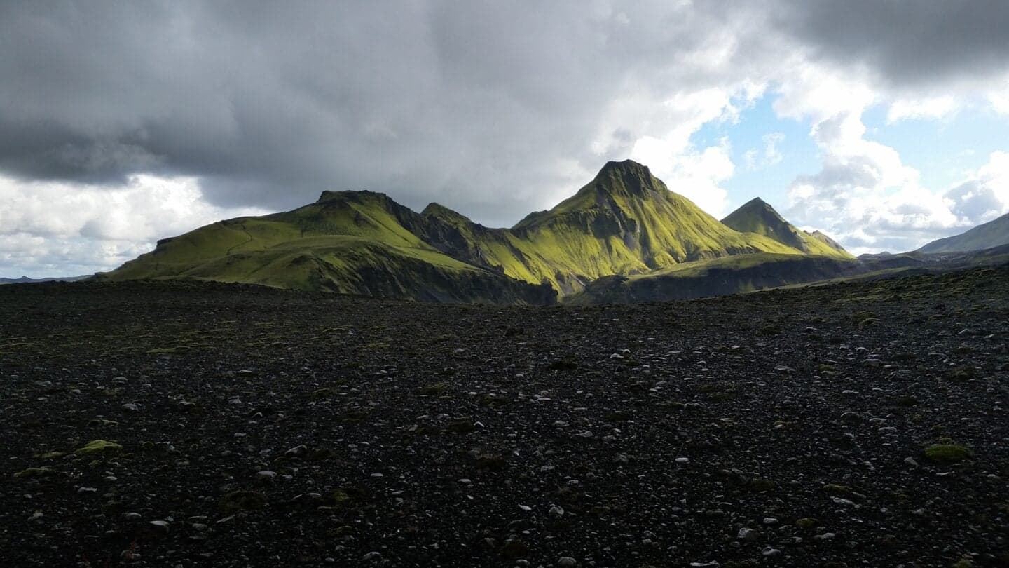 Uxatindar green mountain peaks rising above a dark volcanic highland foreground