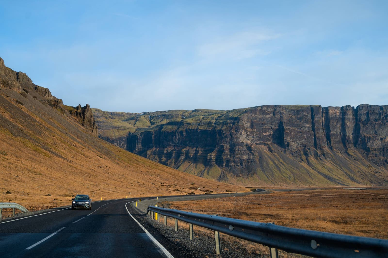 Car driving on a winding road along cliffs on Iceland's South Coast.