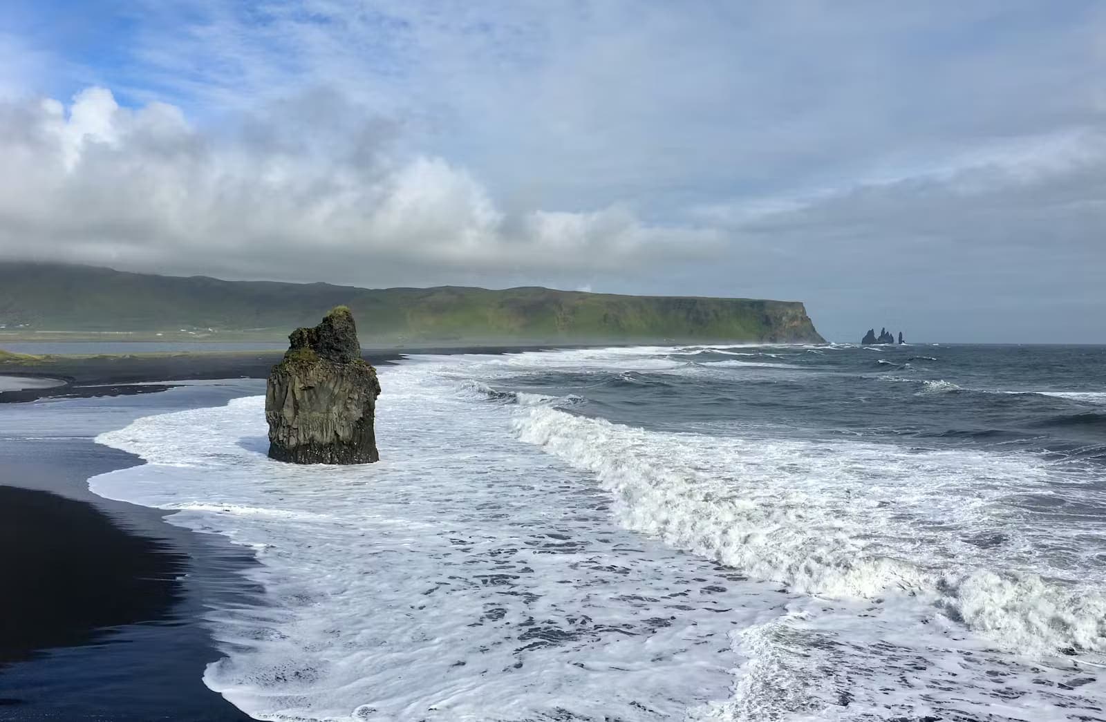 Black sand beach at Reynisfjara with Atlantic surf and sea stacks in South Iceland