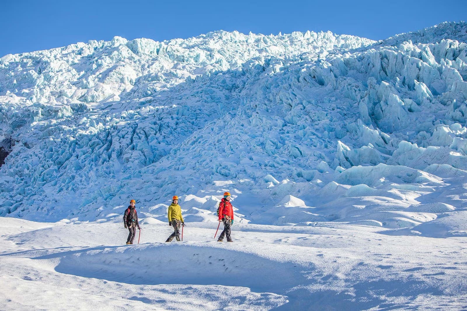 A guided group glacier hiking on an outlet glacier in Skaftafell, Iceland, with vast icy terrain behind them.