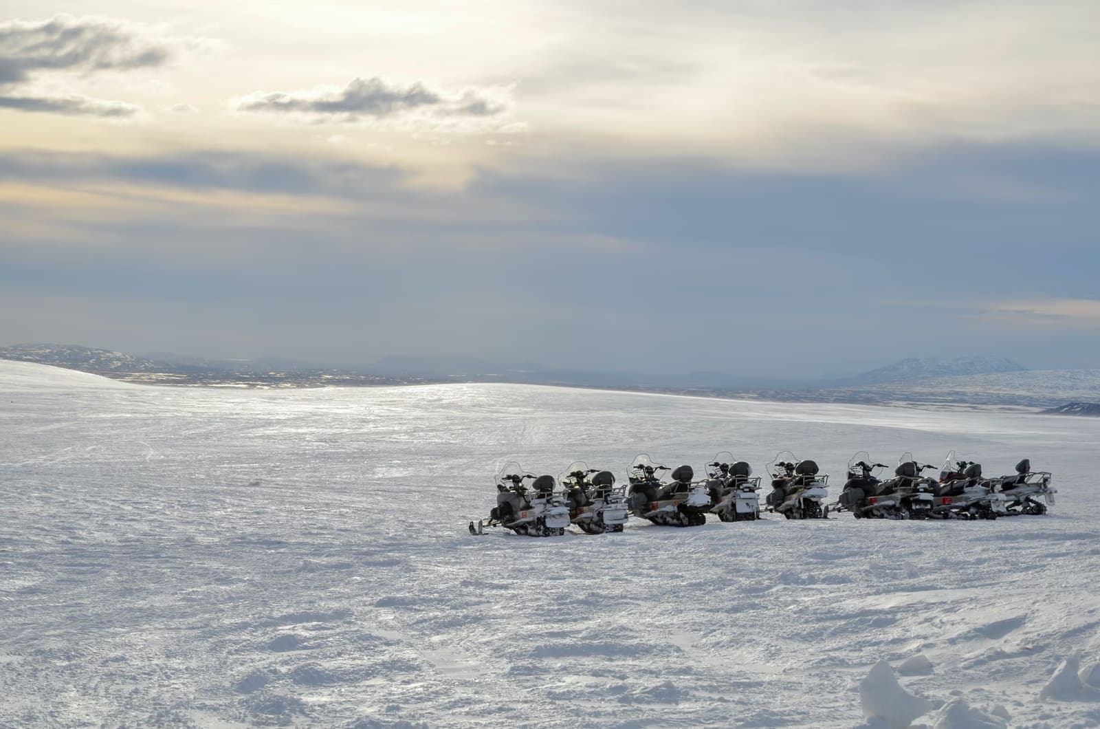 Snowmobiles parked on a wide snowy Langjokull glacier landscape