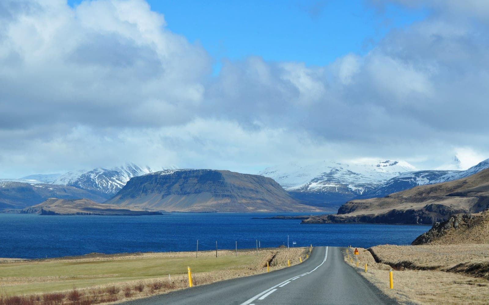 Route 47 descending toward Hvalfjörður beneath snow-covered West Iceland mountains