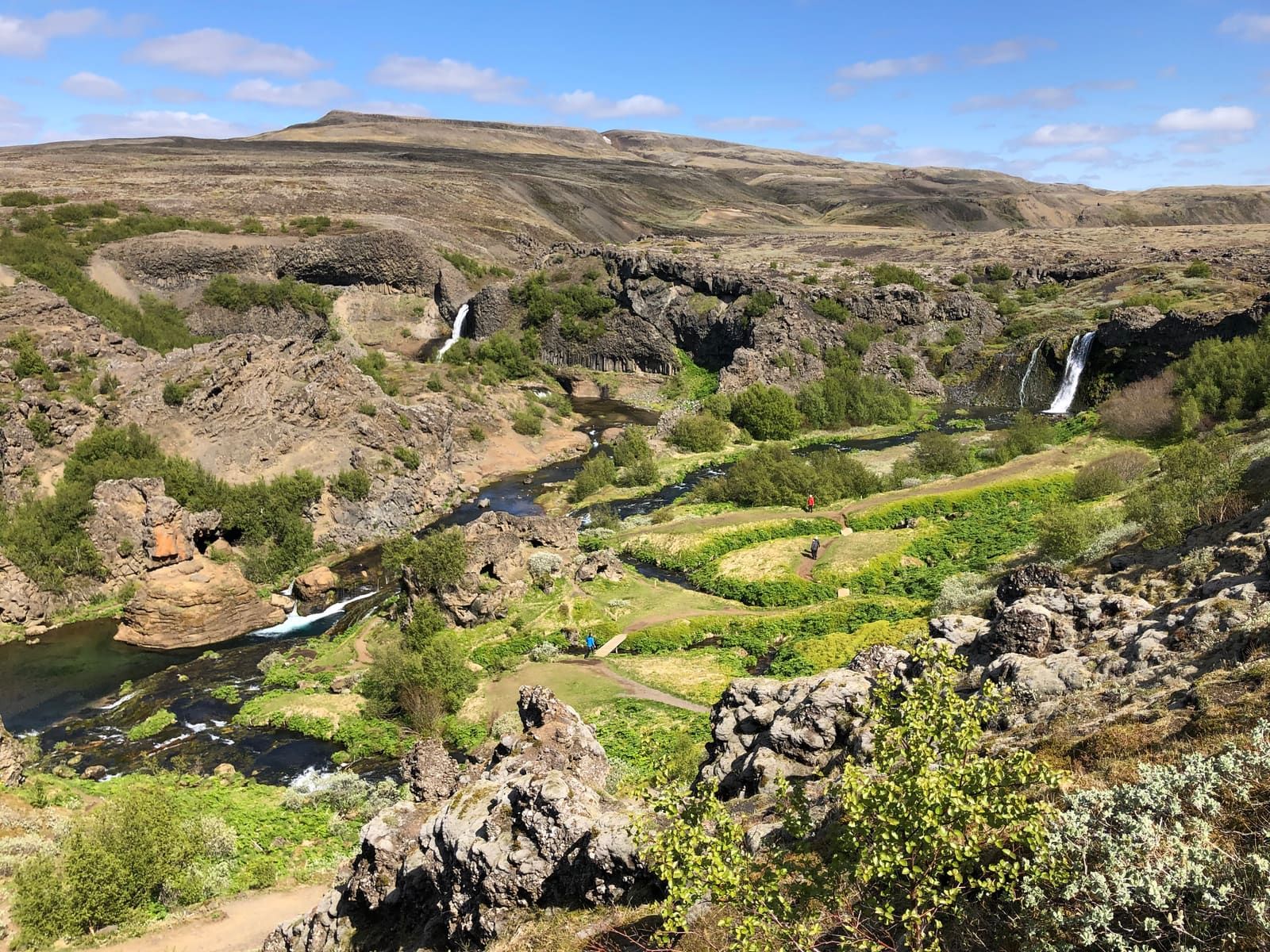 Protected-area landscape around Gjáin with paths, rocky slopes, and waterfalls in Þjórsárdalur.