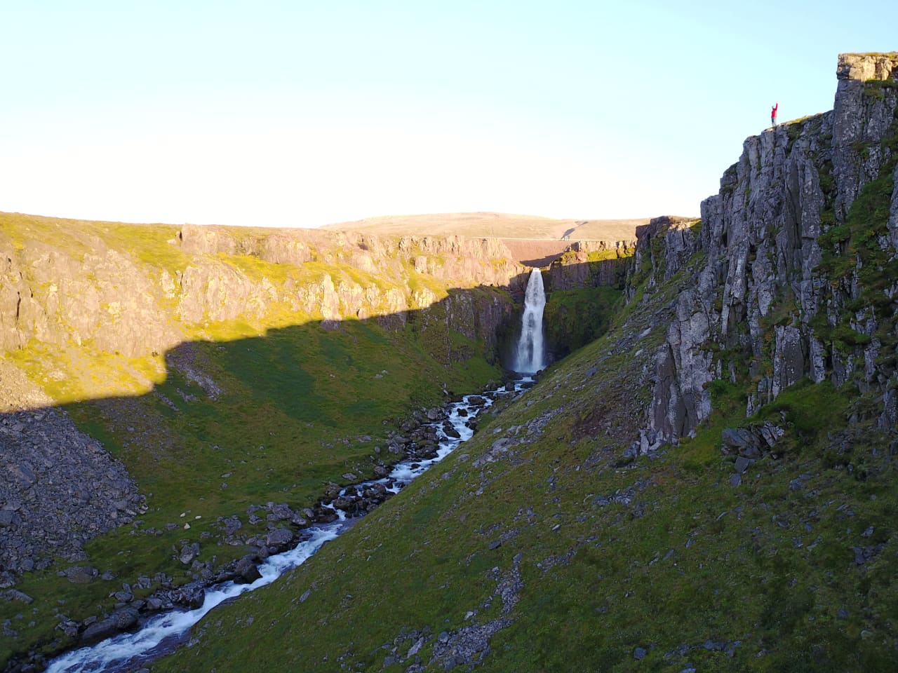 A cliff-side view down the Gljúfursá ravine toward Gljúfursárfoss in East Iceland.