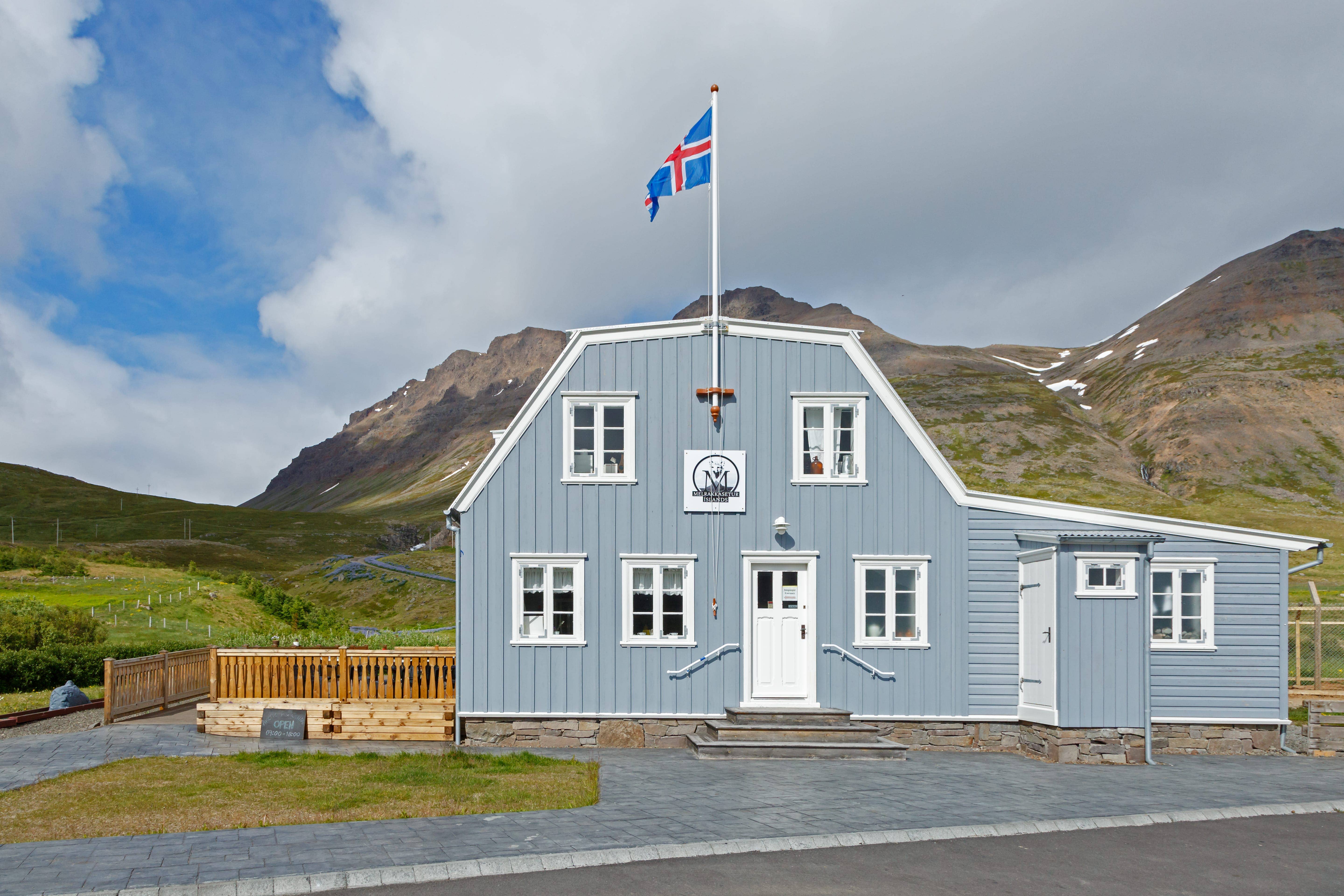 Front view of the Arctic Fox Centre building in Súðavík with mountains behind it.