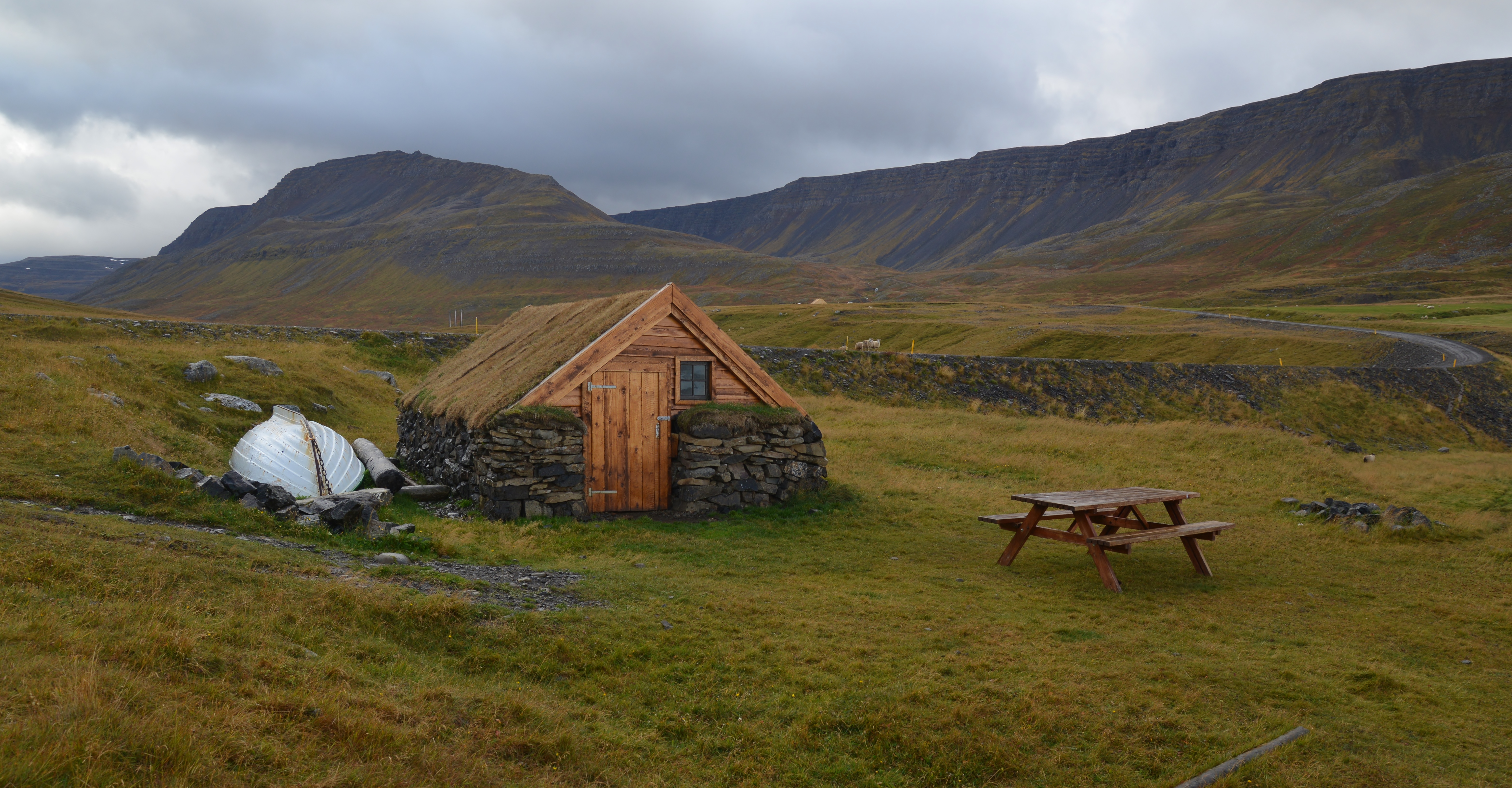 Old fisherman's hut in Staðardalur with open ground and the high valley walls behind it.