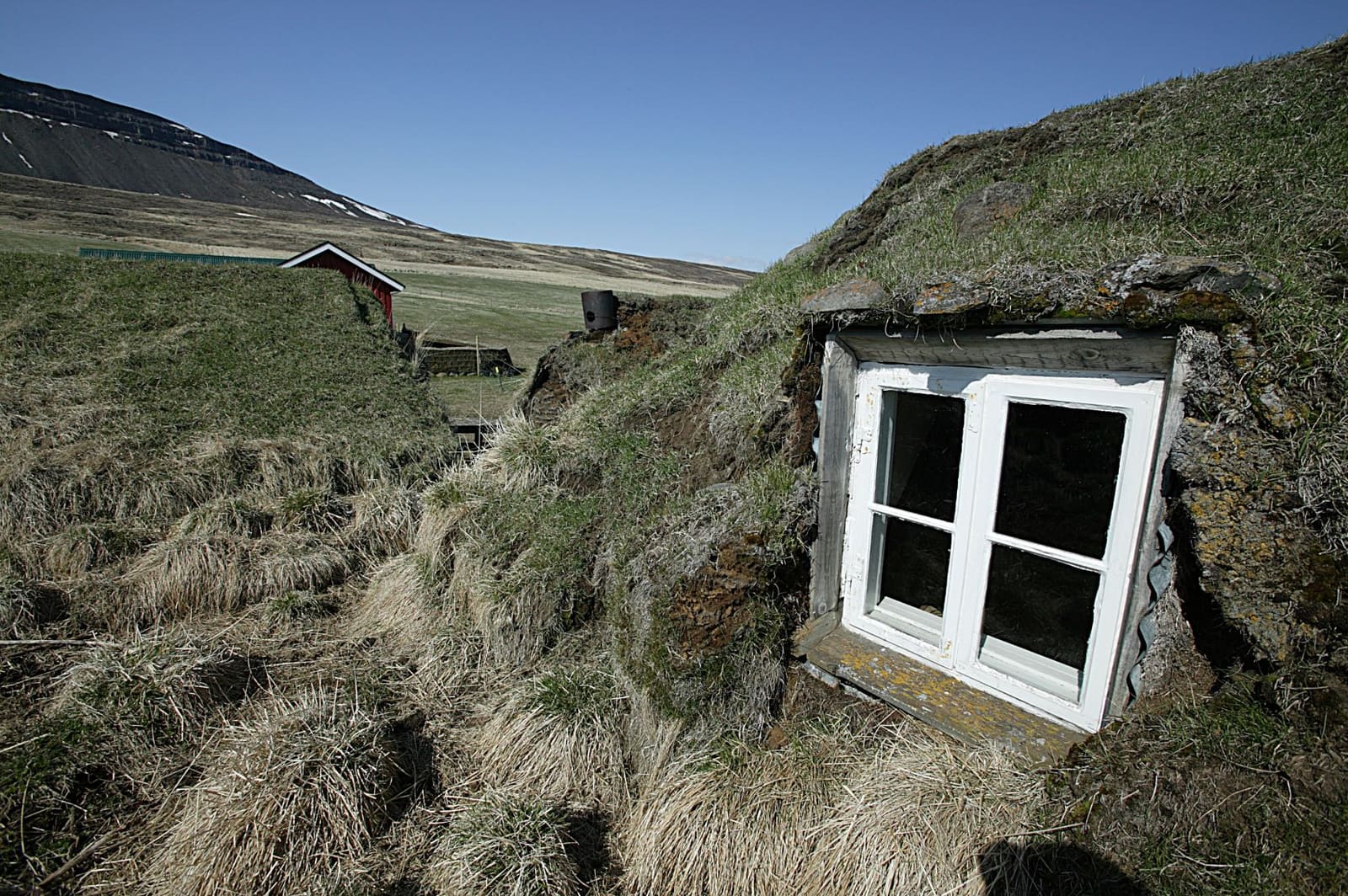 Bustarfell turf farm buildings and hillside setting near Vopnafjörður.