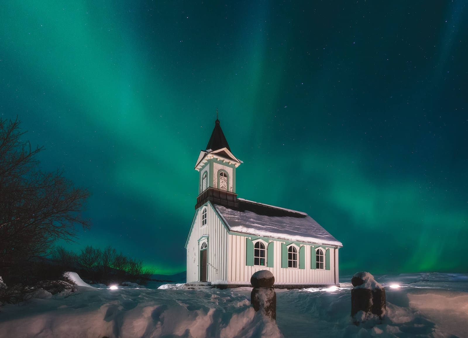 Thingvellir church under northern lights on a snowy winter night.