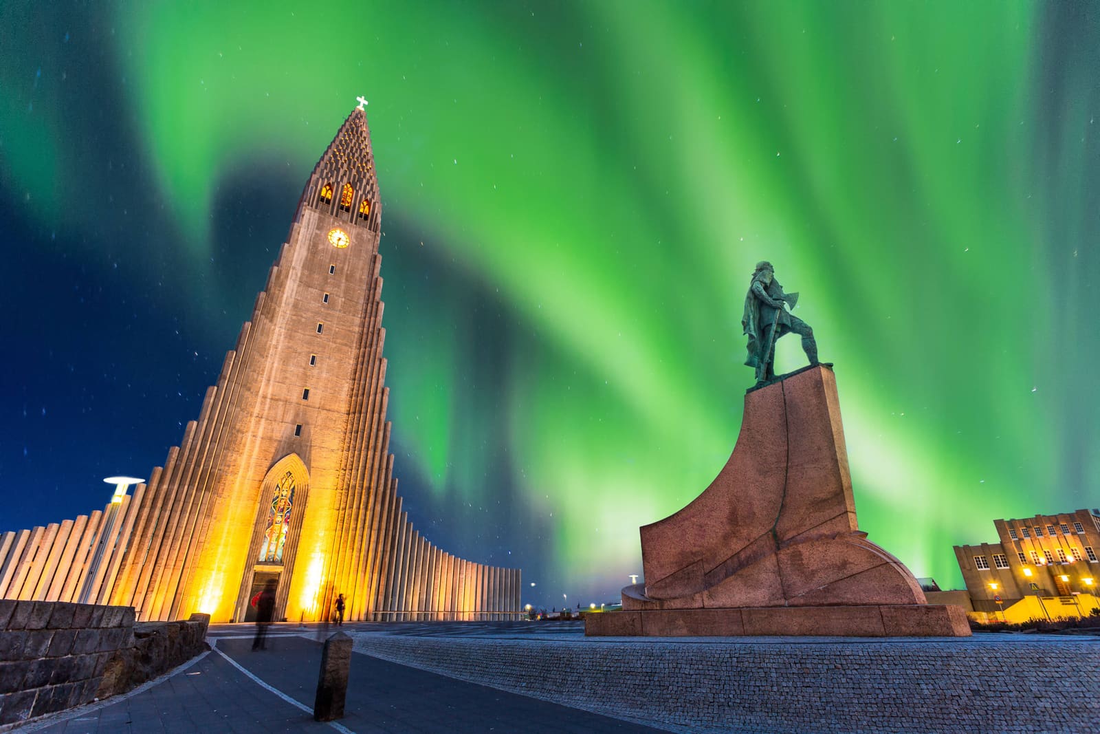 Hallgrimskirkja in Reykjavik below green northern lights.