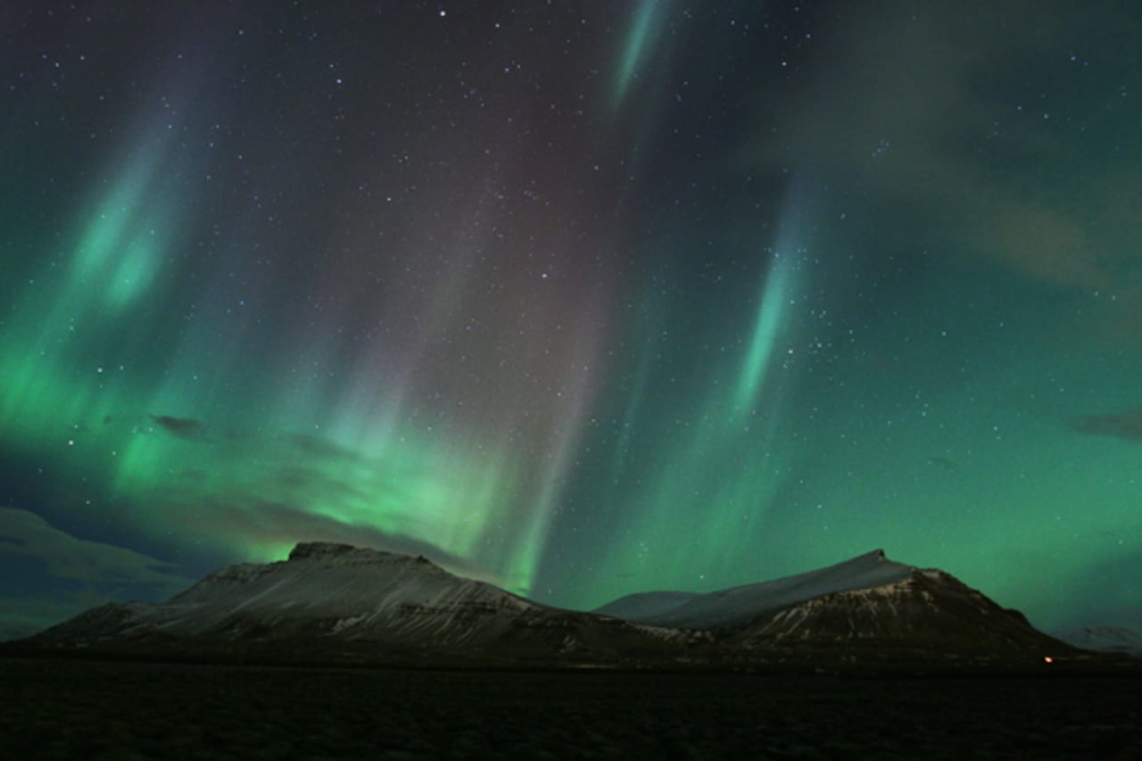 Northern lights over the dark outline of Akrafjall mountain in West Iceland.