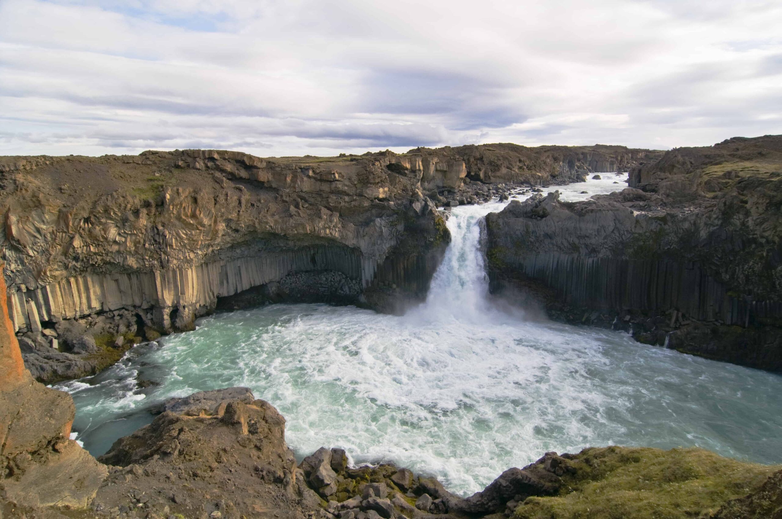 Aldeyjarfoss dropping into a pale river pool below dark basalt columns in North Iceland.