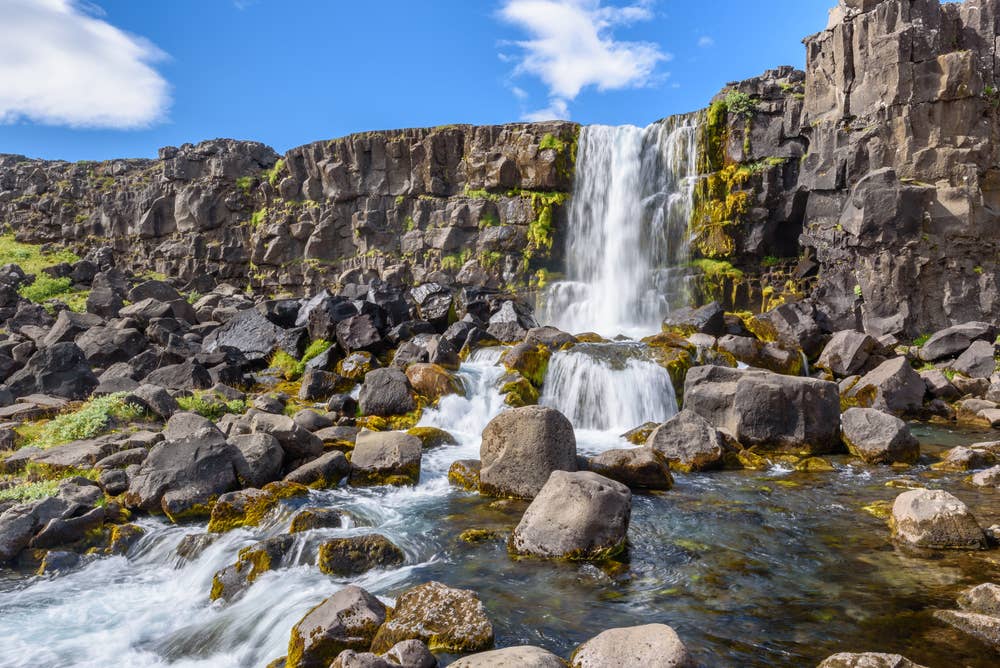 Öxarárfoss waterfall dropping over dark rock in Þingvellir National Park.