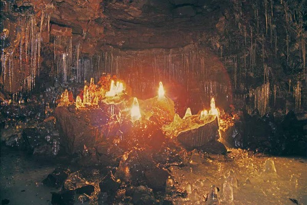 Ice formations glowing inside the dark Arnarker lava cave.